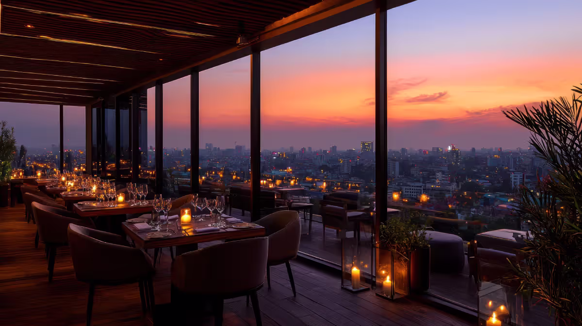 A luxurious rooftop restaurant with fine dining tables, candles on each table, and a spectacular view..